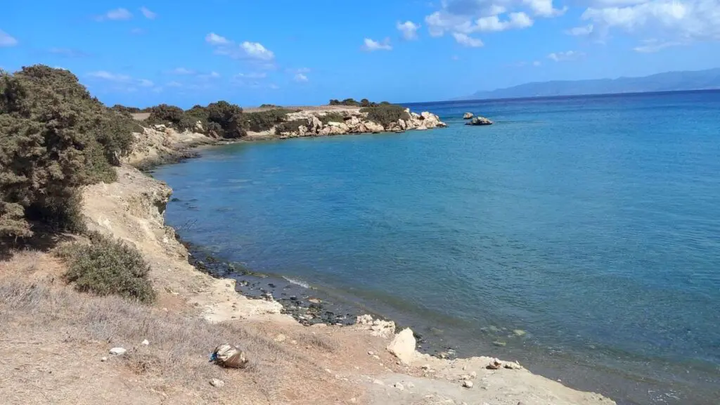 Explore the rocky coastline of Akamas National Park, where clear blue waters meet a partly cloudy sky. Sparse vegetation borders the shore, enhancing this mythological landscape's natural beauty. Ideal for adventure seekers and nature lovers alike.