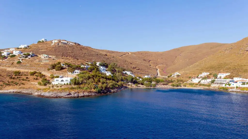 Coastal landscape with houses on a hillside overlooking Kythnos Island's bay, featuring clear blue water.