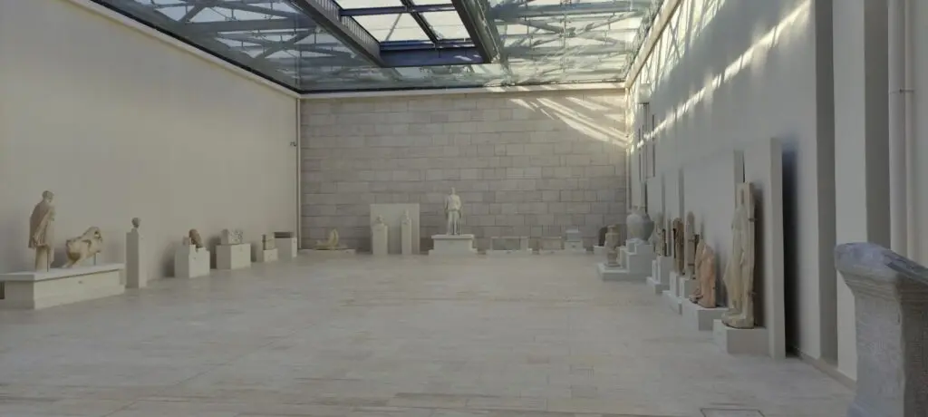 A spacious, well-lit museum gallery with various ancient sculptures and statues, including the renowned Vergina artifacts, displayed on plinths against white walls.