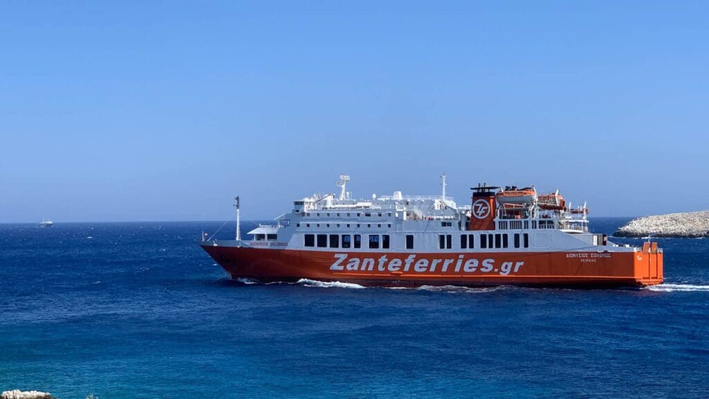 A red Zante Ferries ship sails in the blue sea under a clear sky, making its way to picturesque Serifos Island.