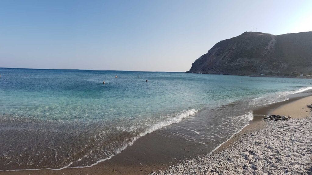 Discover Milos with its calm beaches, where clear blue waters invite a few swimmers and a rocky hill stands majestically in the distance under a clear sky. This hidden gem is among the must-see spots that make Milos Beaches truly unforgettable.