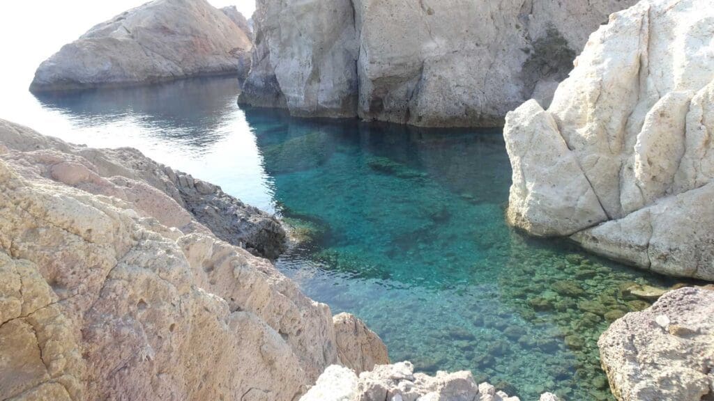 Discover clear turquoise water surrounded by rocky cliffs at one of Milos' must-see spots.