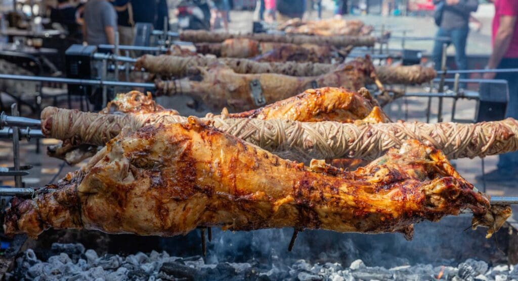 Several whole lambs, a quintessential Greek street food delight, roast on turning spits over an open charcoal fire.
