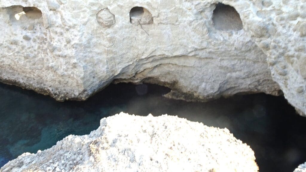 Perched on a rocky cliff with eroded formations, this site is one of Milos Beaches' must-see spots. The dark, narrow cave entrance invites exploration, while the water below is clear and deep—a gem you can't miss.