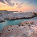 Sarakiniko Beach, Milos Island, Greece -Discover the stunning rocky coastal landscape of Milos at Sarakiniko Beach, where smooth white formations meet turquoise waters under a partly cloudy sunset sky. Perfect for any visitor's guide, this breathtaking view is a must-see for nature lovers and photographers alike.