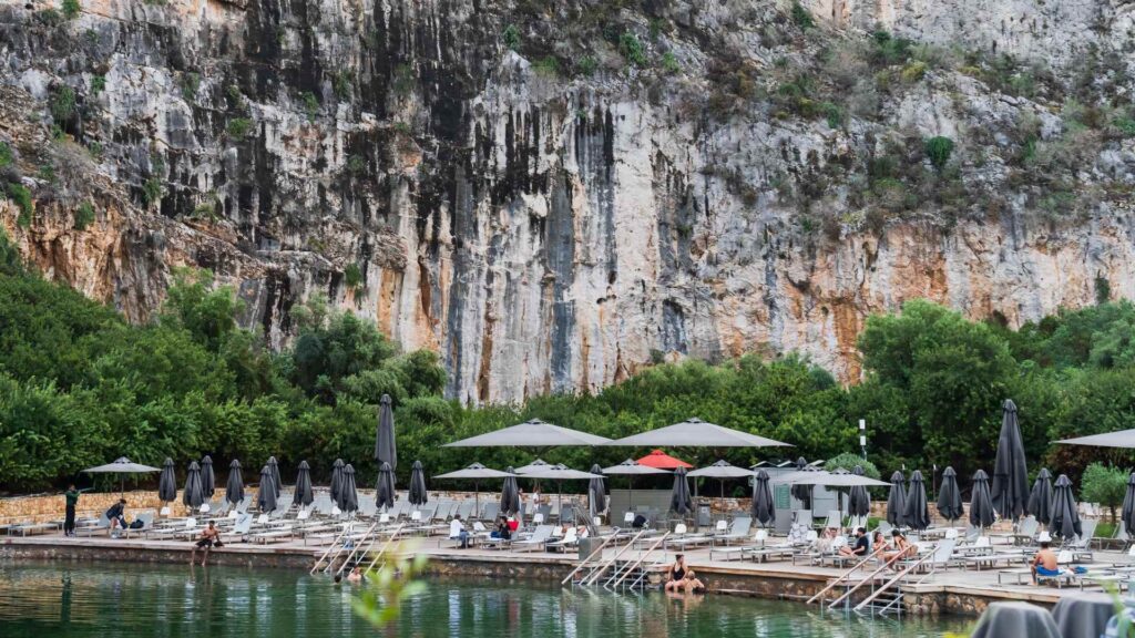 Nestled against a rocky cliff and lush greenery, this stunning outdoor pool area near Athens is perfect for unwinding. Lounge chairs and umbrellas invite relaxation, making it one of the best things to do. Imagine spending a serene day here before diving into the city's vibrant Christmas festivities.