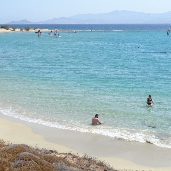 Experience the panoramic beauty of a sandy beach where the clear blue sea meets distant hills under a bright sky. Whether you're enjoying the water or lounging onshore, this idyllic setting invites you to explore where to stay in Paros for the perfect getaway.