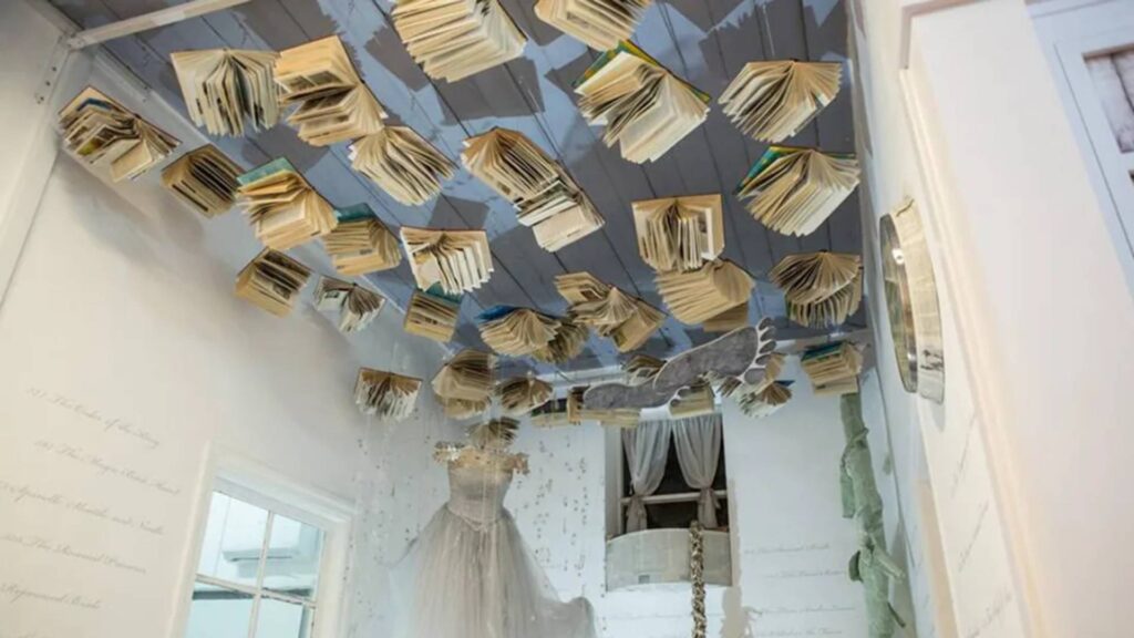 In Nicosia, explore a whimsical room where open books hang from the ceiling like drifting clouds, while a mannequin in a white dress stands gracefully beneath. A local travel guide might suggest it as one of the unique things to do in this vibrant city.