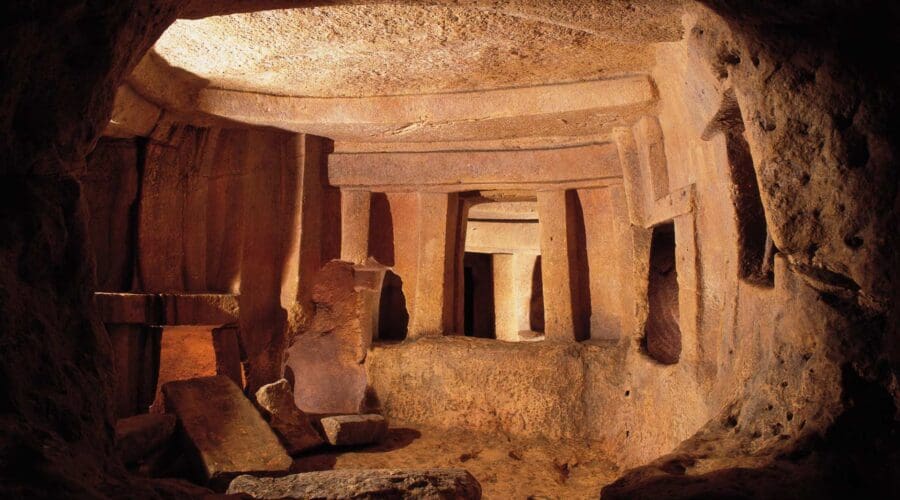 Ancient stone chamber with upright pillars and large slabs, lit by warm light, showing weathered surfaces and rough floor—a remarkable site among the must-see places to visit in Cyprus.