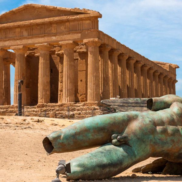 Temple of Concordia at the Valley of the Temples in Agrigento, Sicily, with the temple standing on the ridge above olive trees and the surrounding landscape.