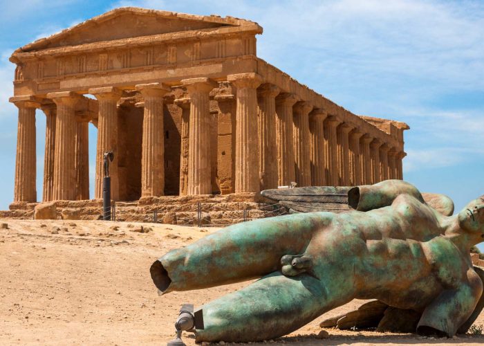 Temple of Concordia at the Valley of the Temples in Agrigento, Sicily, with the temple standing on the ridge above olive trees and the surrounding landscape.